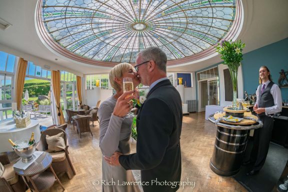 A couple sharing a moment in an elegant venue with a glass dome ceiling.