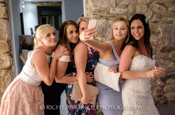 A group of five women posing for a selfie in a casual indoor setting.