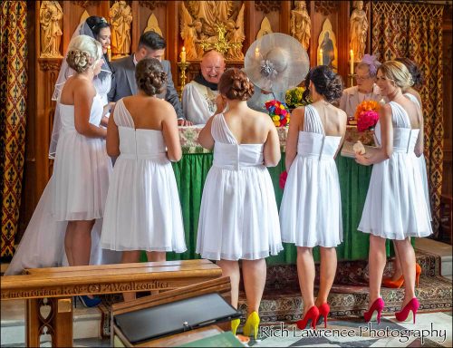 Bride and bridesmaids in white dresses at a wedding ceremony, gathered around a table.